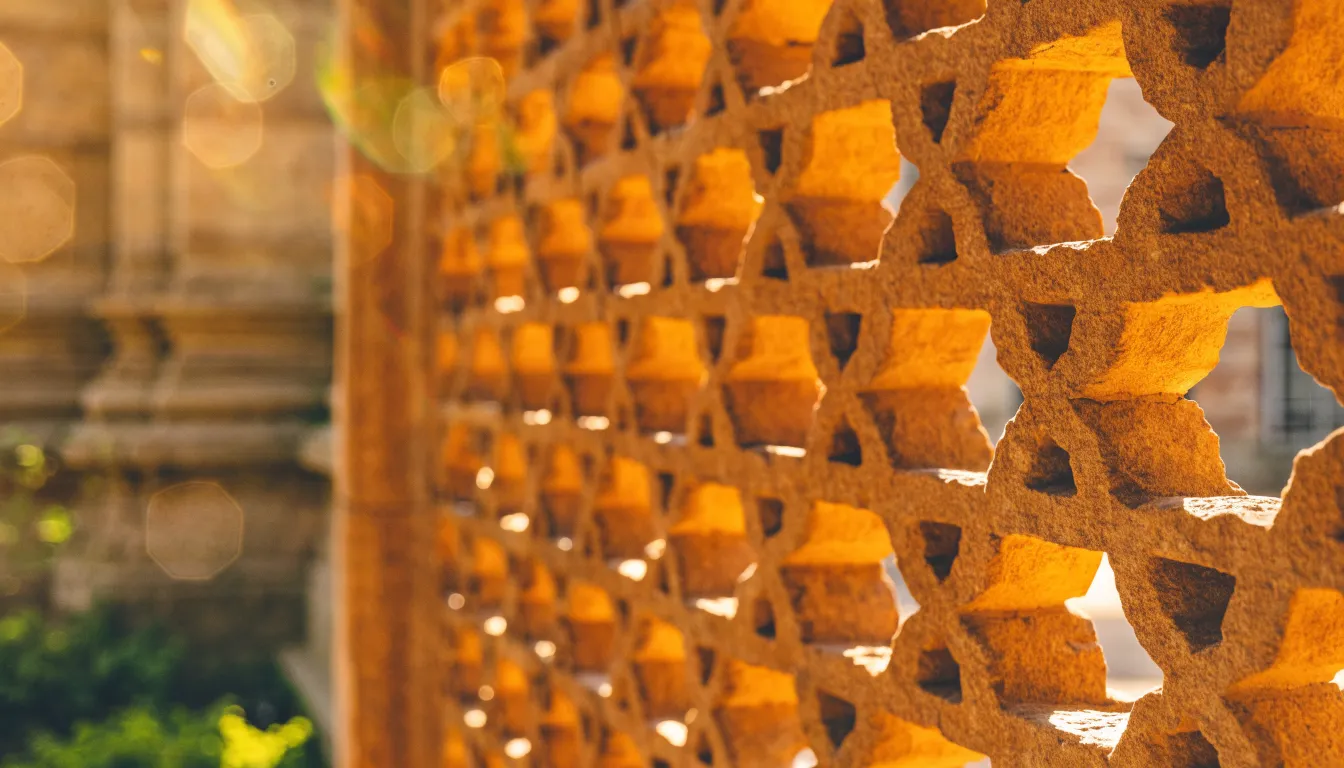 Carved sandstone jaali screen with golden light through its lattice